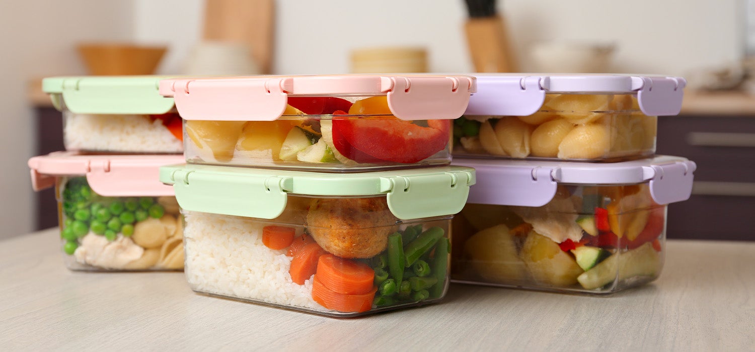 Mehrere Tupper-Boxen mit vorbereiteten Mahlzeiten stehen auf einer Küchenzeile