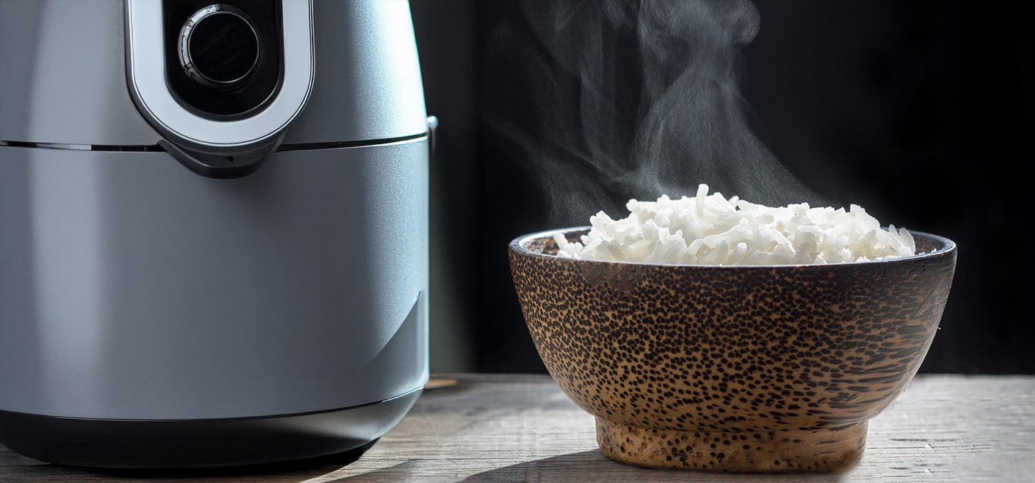 Ein Airfryer und daneben eine Schüssel Reis