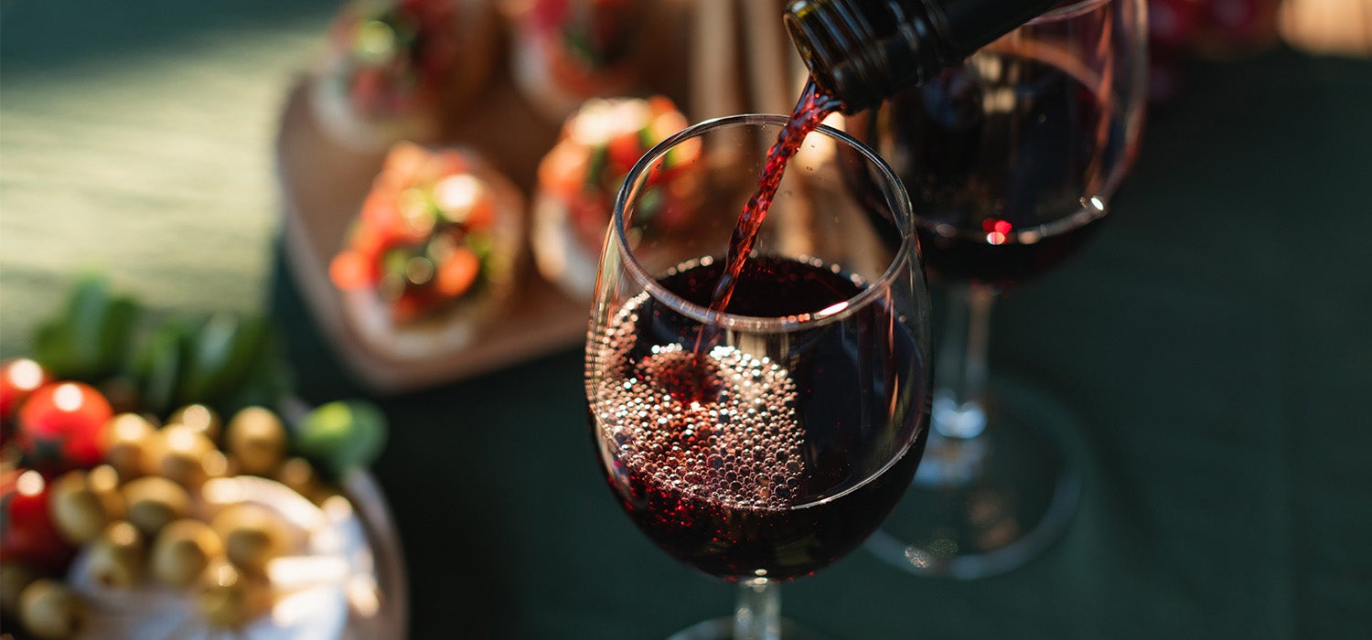 Rotwein wird am Tisch mit dem Weihnachtsessen in ein Glas geschüttet