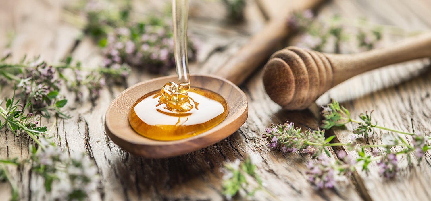 Honig wird gerade auf einen Holzlöffel gegossen. 