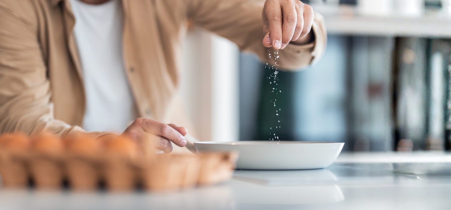 Hand würzt Rührei mit Salz