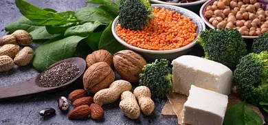 Linsen, Bohnen, Kichererbsen, Nüsse, Spinat, Brokkoli und Tofu auf dunkler Oberfläche