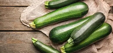 Mehrere frische Zucchini auf Jutestoff auf rustikalem Holztisch