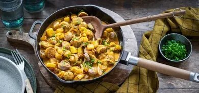 Kartoffel-Bratwurst-Pfanne mit Kartoffelwürfeln, Wurstscheiben und Schnittlauch in Gusseisenpfanne