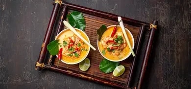 Zwei Schalen Ramen mit Garnelen, Chili, Zitronengras und Limetten auf Holztablett