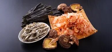 Kombu-Algen, Shiitake-Pilze, Bonitoflocken und getrocknete Fische auf schwarzer Oberfläche