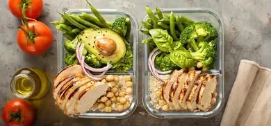 Zwei Glasboxen mit Hähnchenbrust, Reis, Kichererbsen, Brokkoli, Bohnen, Avocado und Zwiebeln