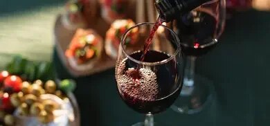Rotwein wird am Tisch mit dem Weihnachtsessen in ein Glas geschüttet