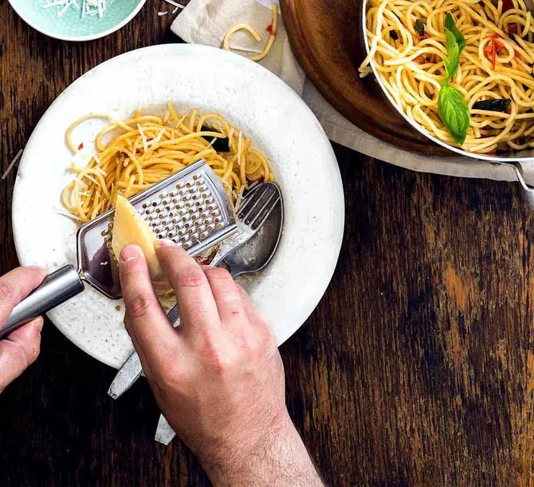 Parmesan wird auf Pasta-Gericht gerieben