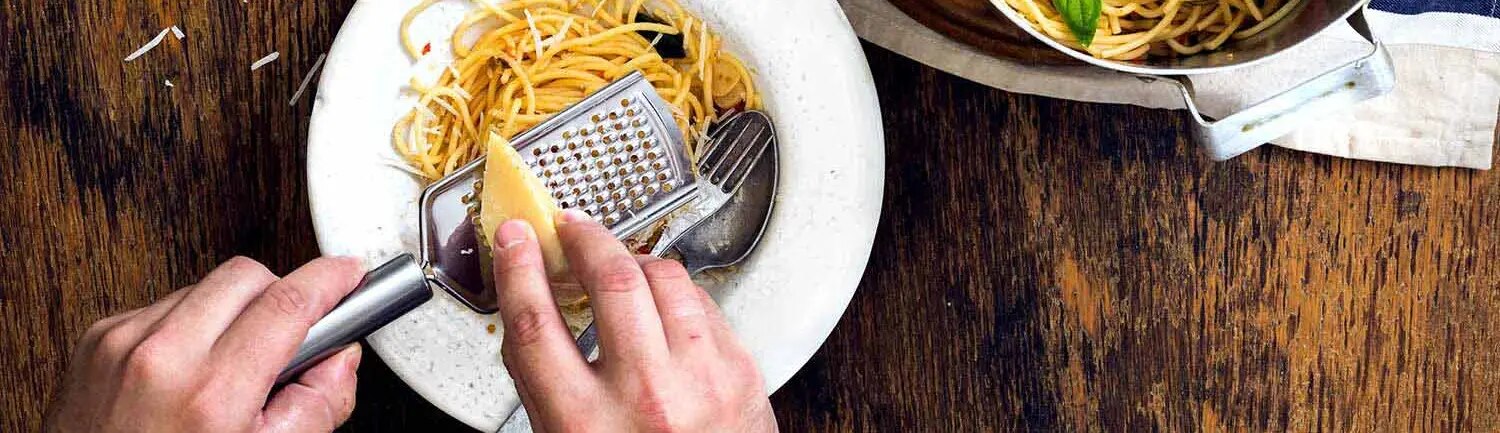 Parmesan wird auf Pasta-Gericht gerieben