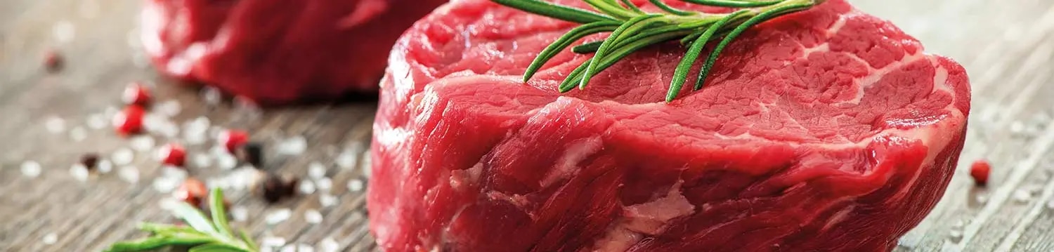 Rohe Rindfleischstücke mit Kräuterzweig auf Brett