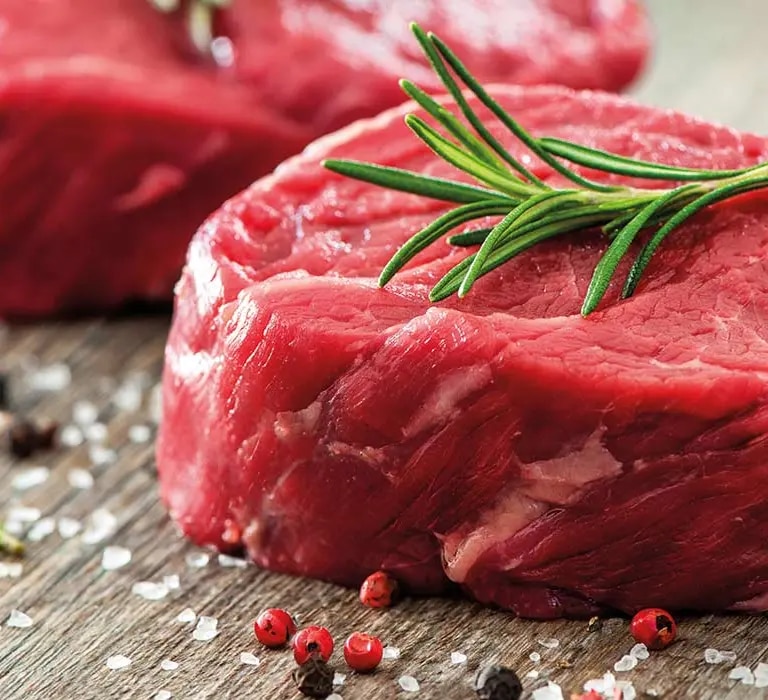 Rohe Rindfleischstücke mit Kräuterzweig auf Brett