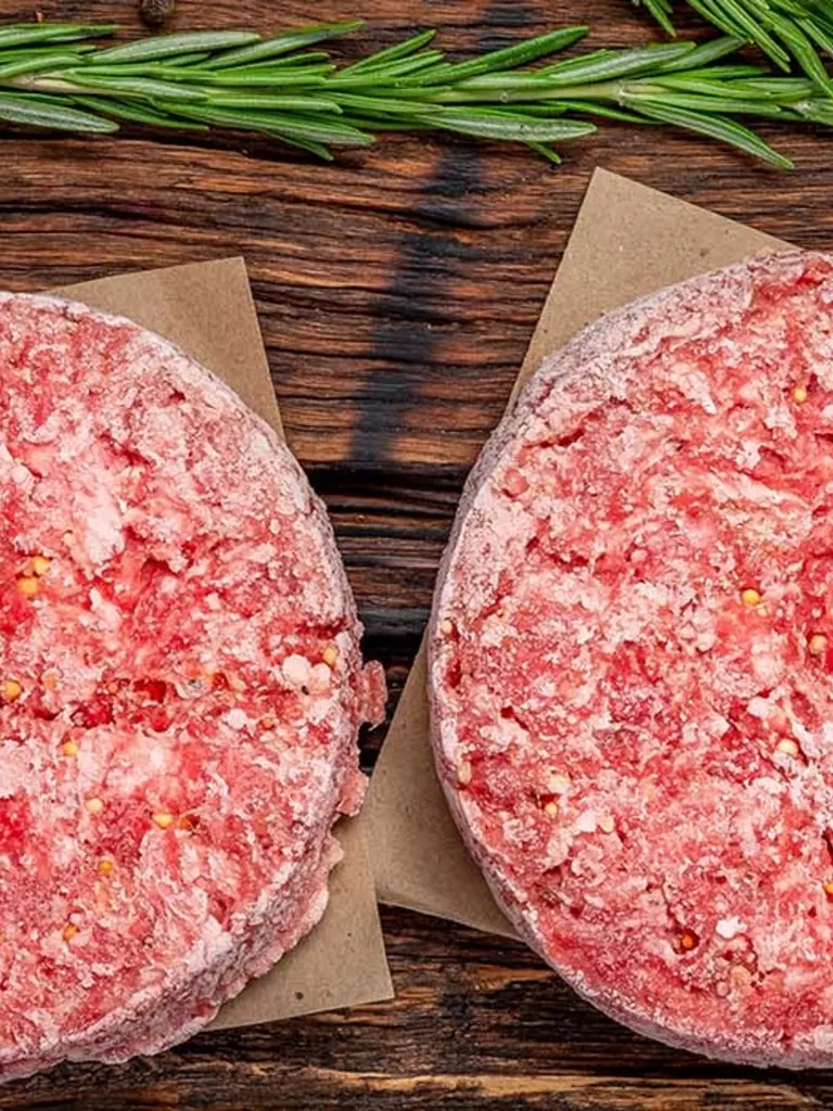 Hackfleisch schnell auftauen – gefrorene Burger-Patties auf Holzbrett