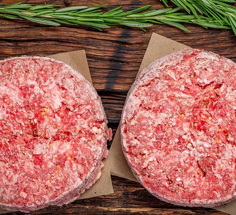 Hackfleisch schnell auftauen – gefrorene Burger-Patties auf Holzbrett