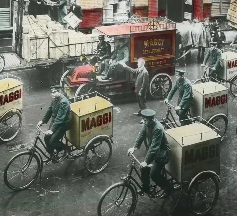 Historische Bilder von Männern auf Fahrrädern mit MAGGI Anhängern.