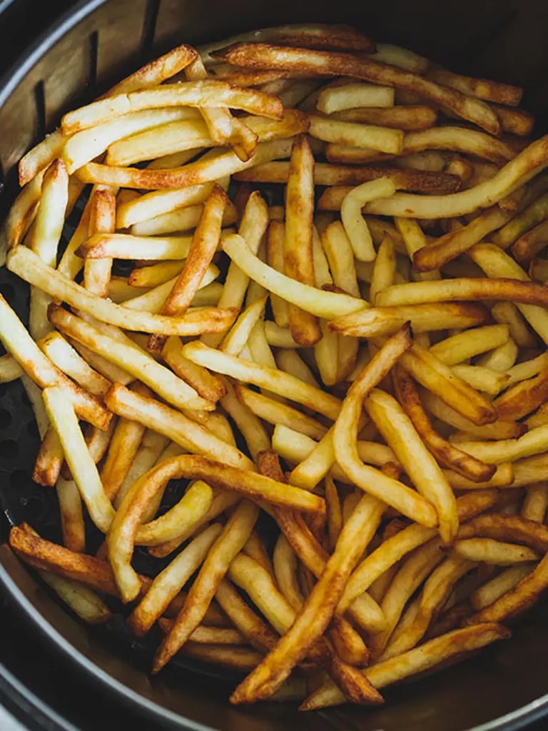 Knusprige goldbraune Pommes in einem Airfryer Korb