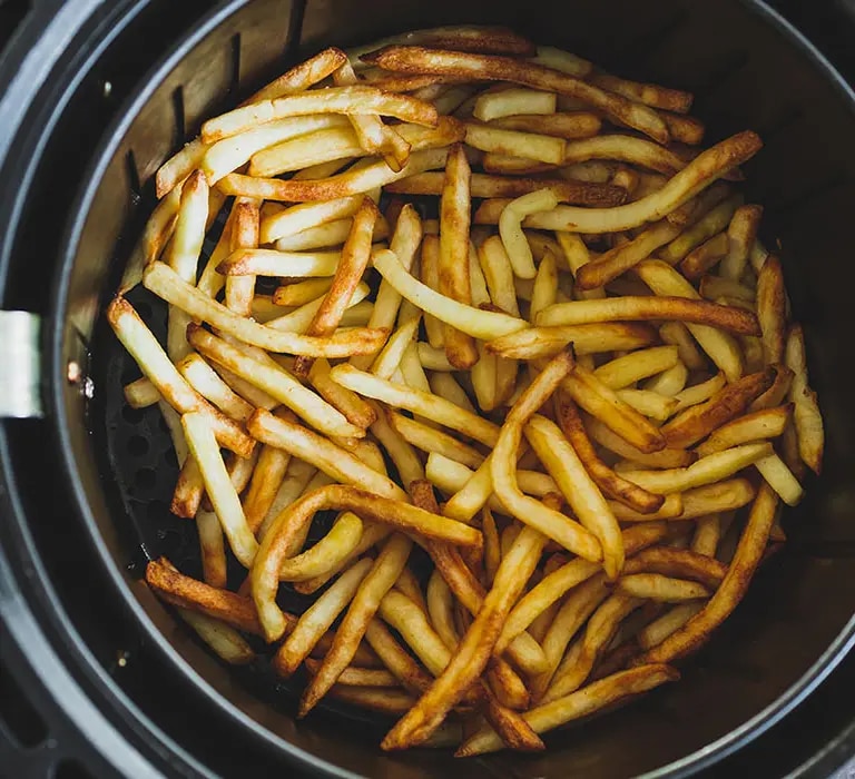 Knusprige goldbraune Pommes in einem Airfryer Korb