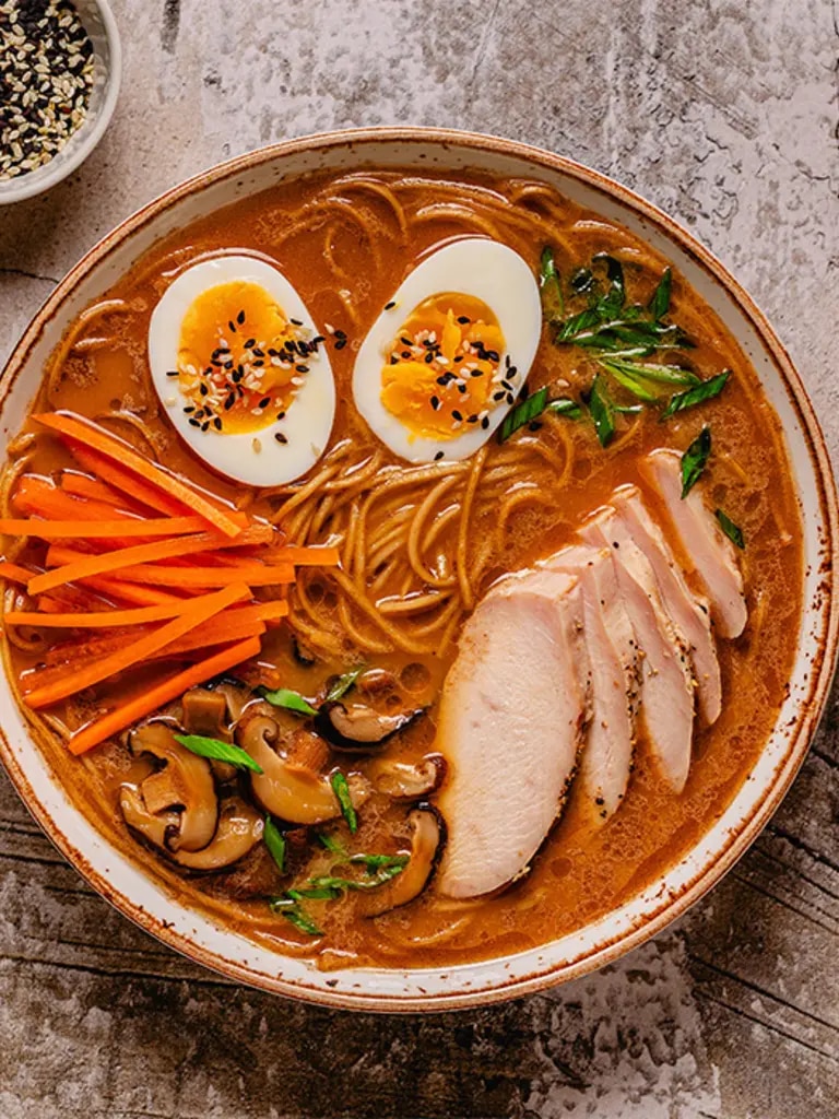 Instant Ramen mit verschiedenen Toppings: EI, Karotte, Fleisch Champignons und Kräutern.