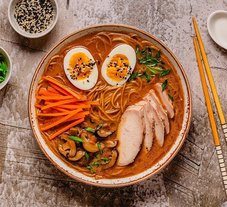 Instant Ramen mit verschiedenen Toppings: EI, Karotte, Fleisch Champignons und Kräutern.