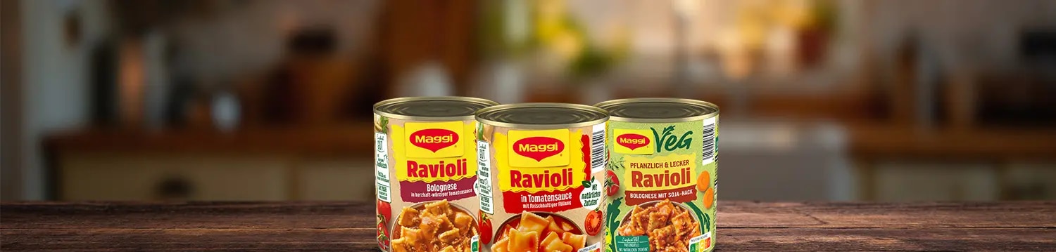 Drei Dosen Maggi Ravioli auf Holzoberflaeche, Sorten Bolognese, Tomatensauce und vegan