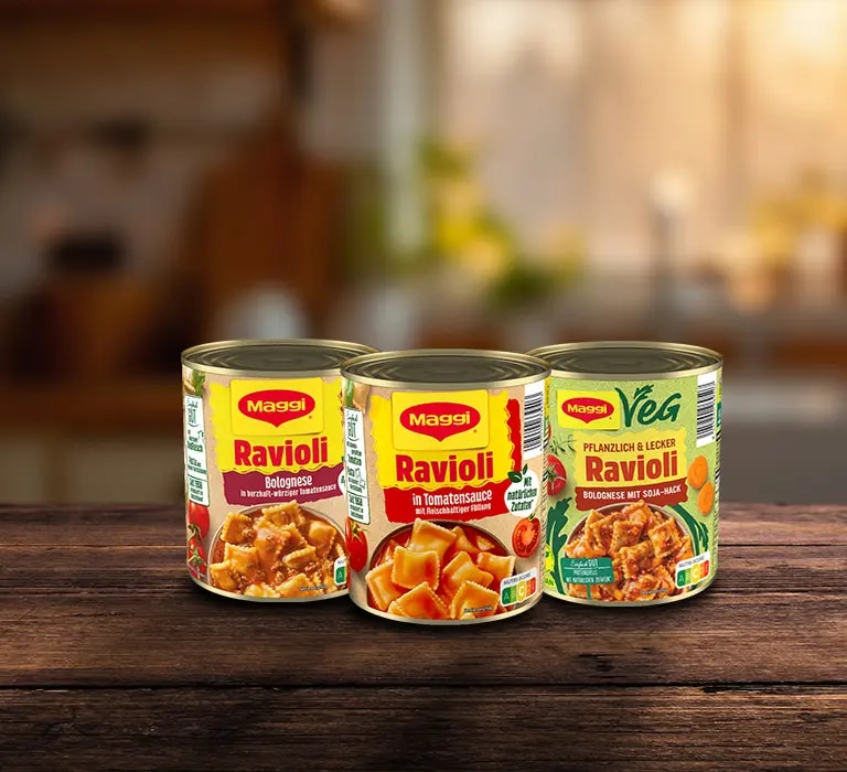 Drei Dosen Maggi Ravioli auf Holzoberflaeche, Sorten Bolognese, Tomatensauce und vegan
