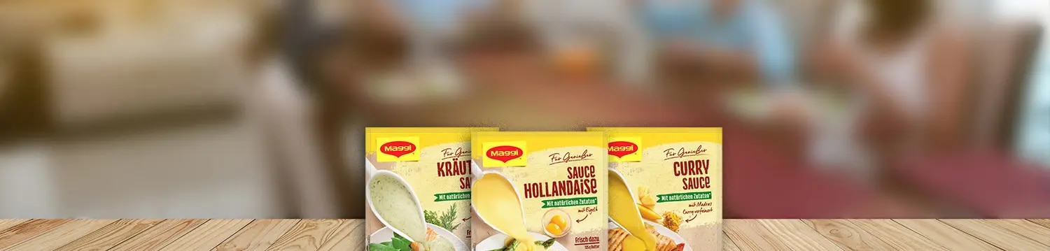 Drei Maggi Saucenpackungen mit Kräutersauce, Sauce Hollandaise und Currysauce auf Holztisch vor Küche