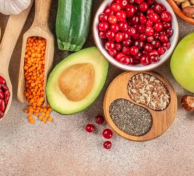 Avocado, Apfel, Cranberries, Zucchini, Spinat, Bohnen, Linsen, Kichererbsen, Nüsse und Samen auf Tischfläche