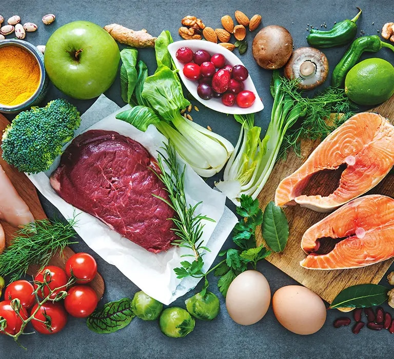 Lachs, Hähnchenbrust, Rindfleisch, Eier, Bohnen, Linsen, Nüsse und Gemüse auf Tischfläche