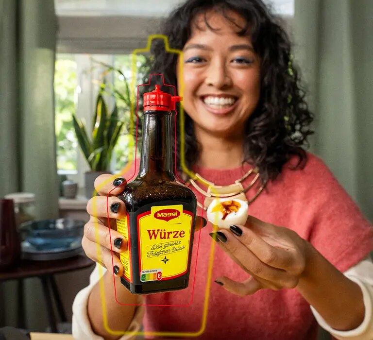 Maggi Würze Flasche und halbes Ei in einer Hand vor Fenster mit Pflanzen, Motiv der 140 Jahre Kampagne