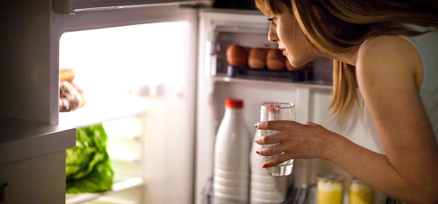 Frau nachts vor geöffnetemKühlschrank