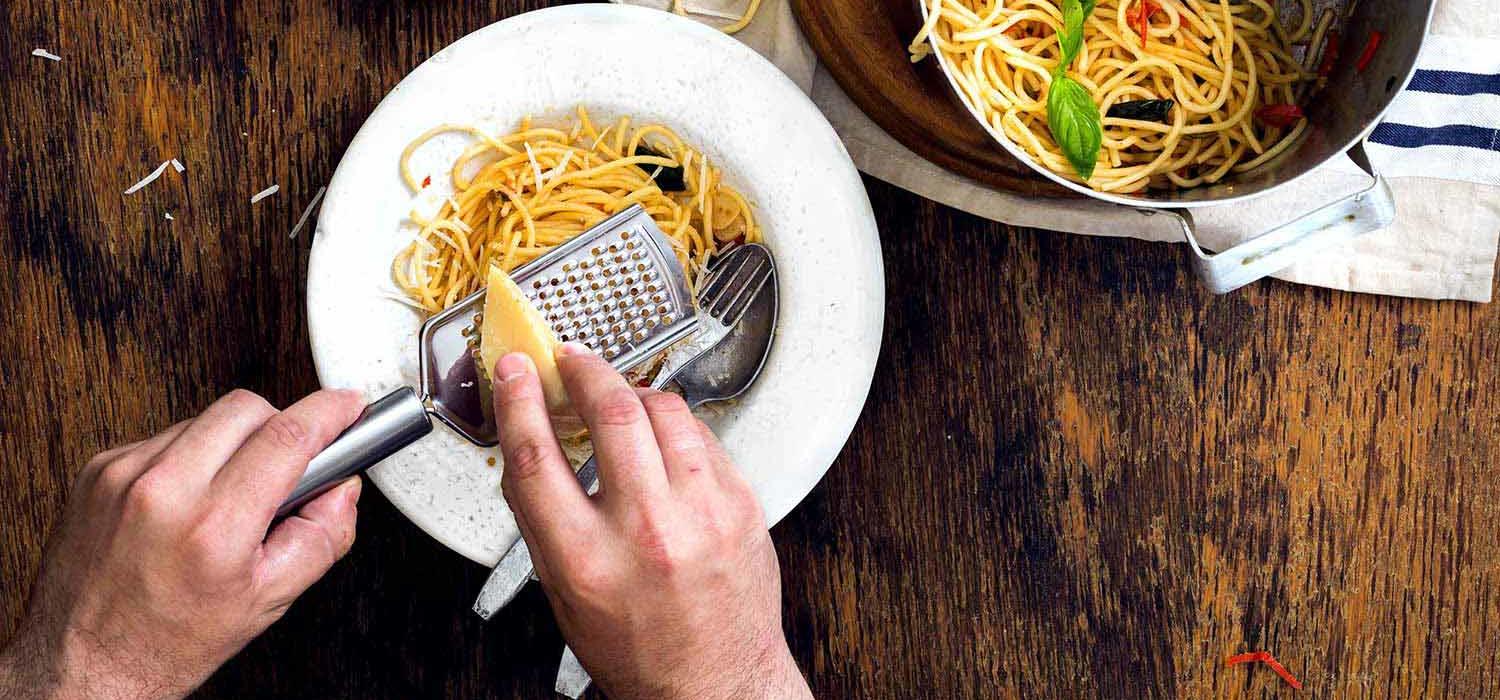 Parmesan wird auf Pasta-Gericht gerieben