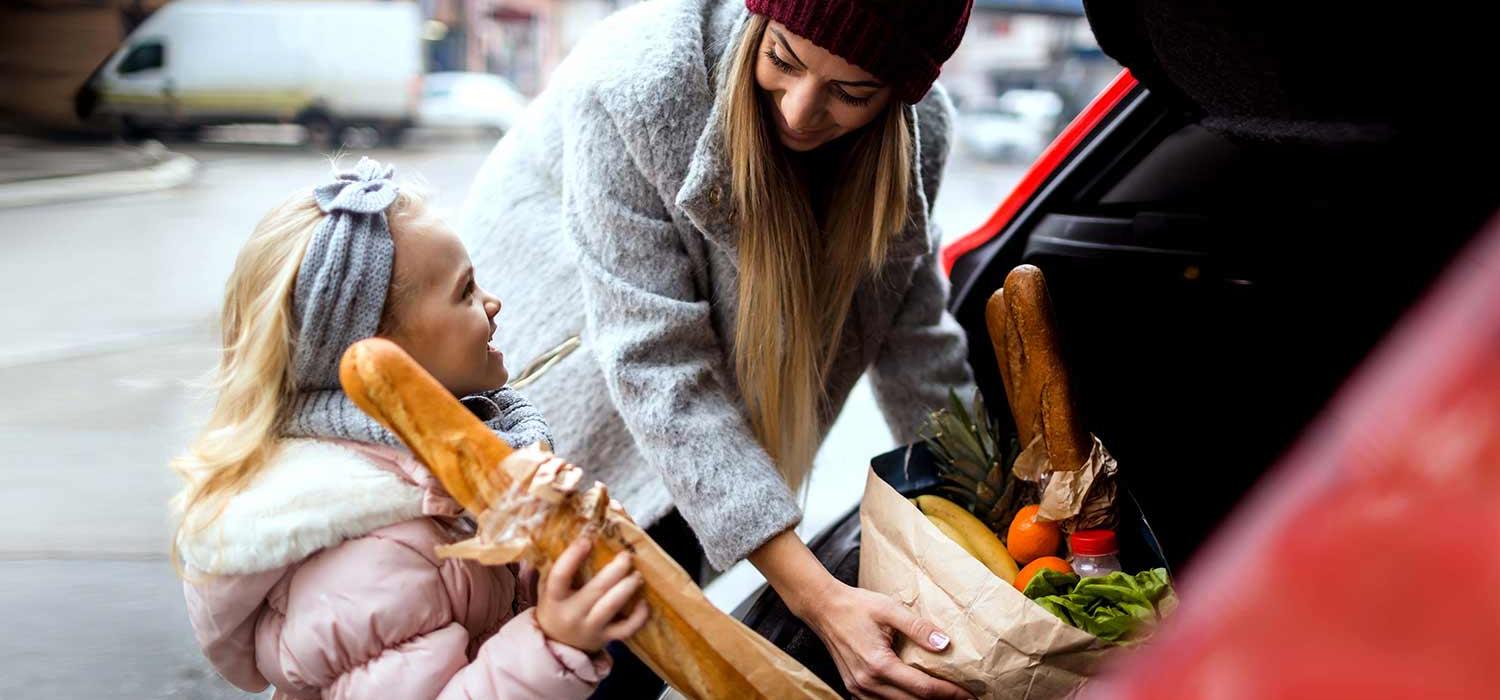 Mutter und Tochter packen Einkäufe ins Auto