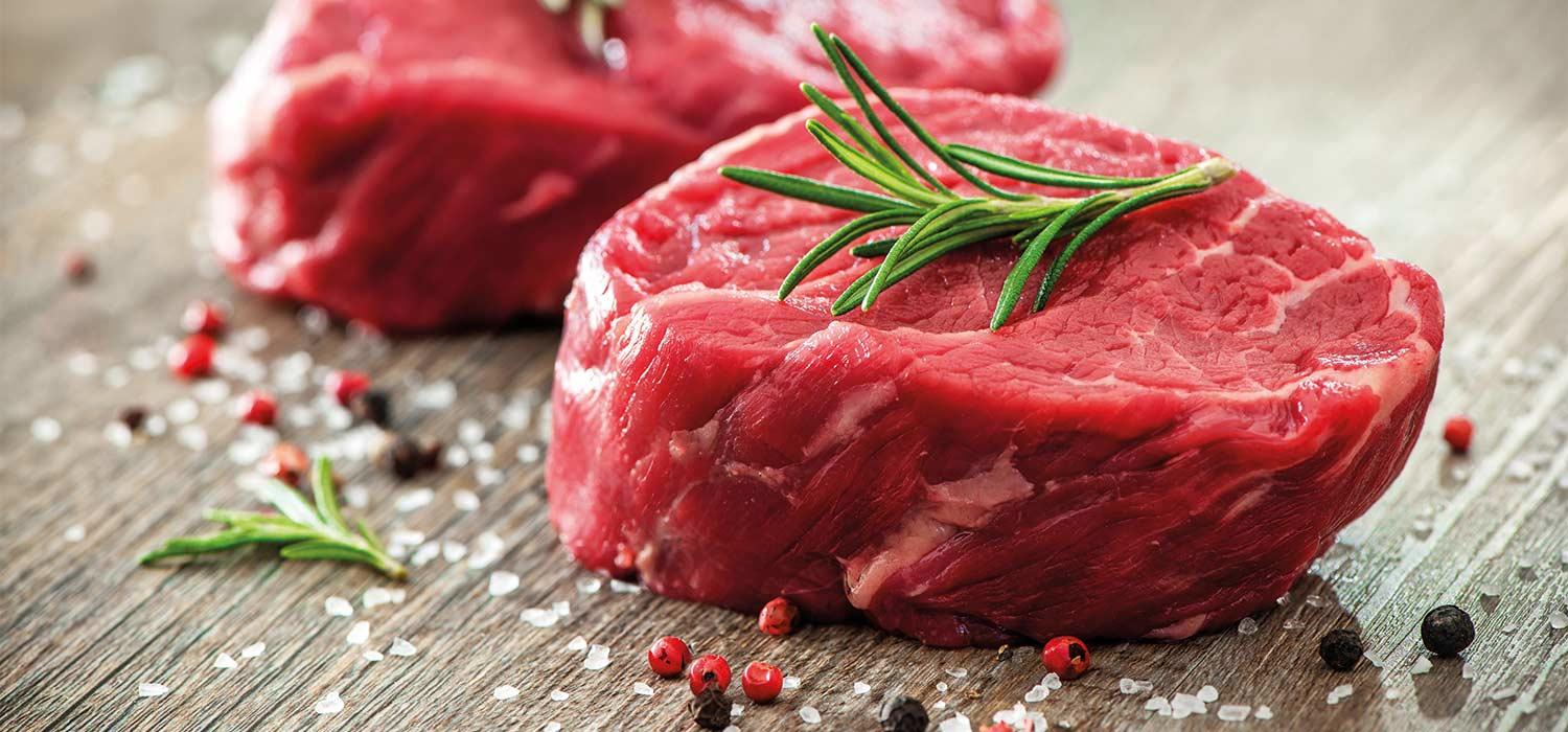 Rohe Rindfleischstücke mit Kräuterzweig auf Brett