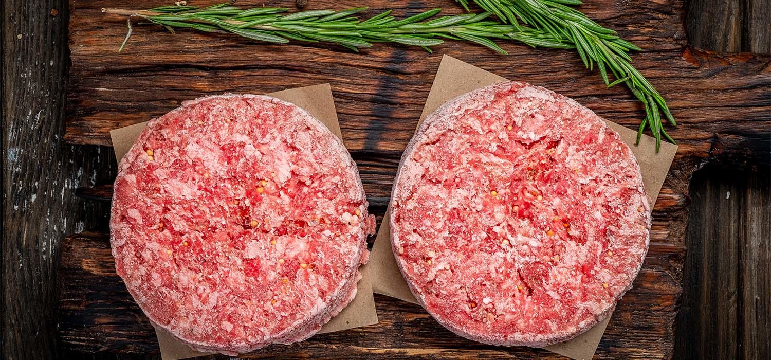 Hackfleisch schnell auftauen – gefrorene Burger-Patties auf Holzbrett