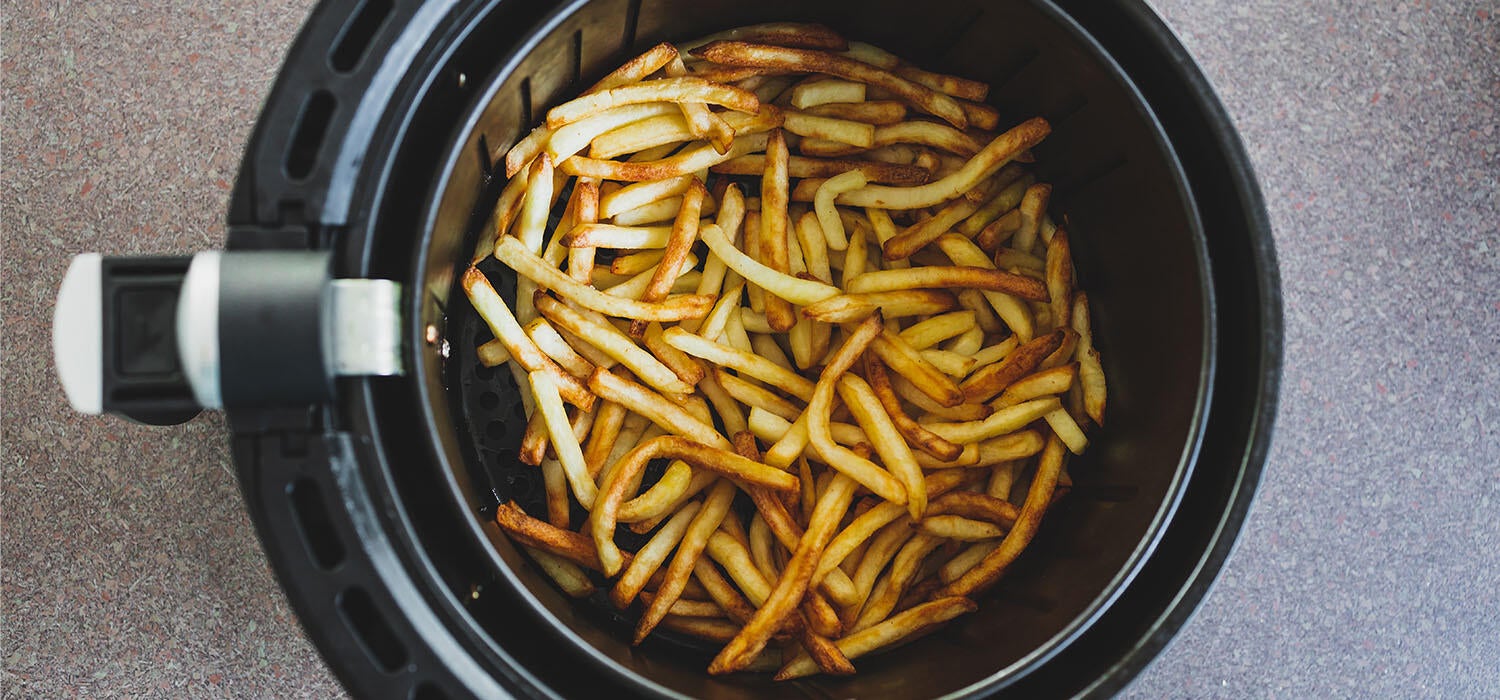 Knusprige goldbraune Pommes in einem Airfryer Korb