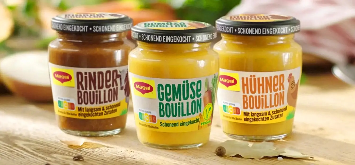 Drei Maggi Bouillon-Glaeser mit Rinder-, Gemuese- und Huehnerbouillon auf Holzoberflaeche