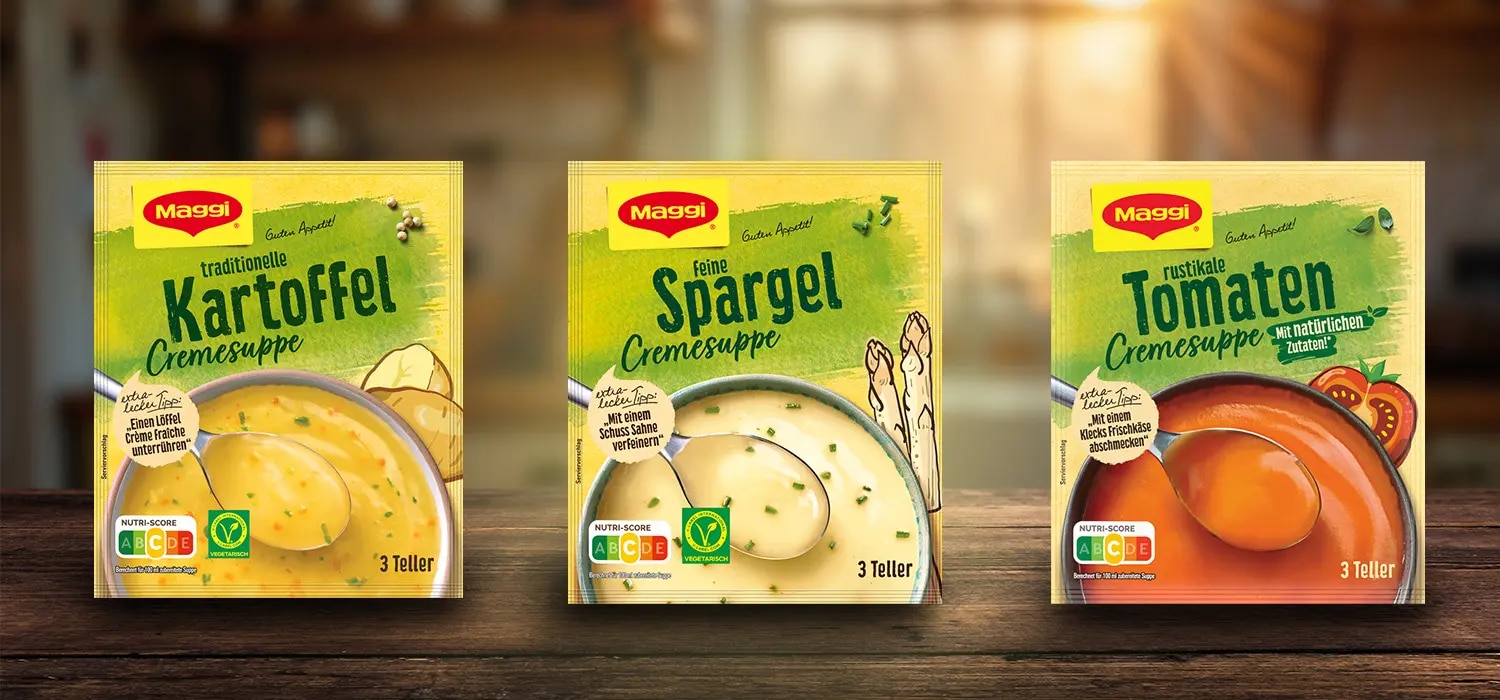Drei Maggi Cremesuppen Packungen mit Kartoffel-, Spargel- und Tomatensuppe auf Holztisch vor Kueche