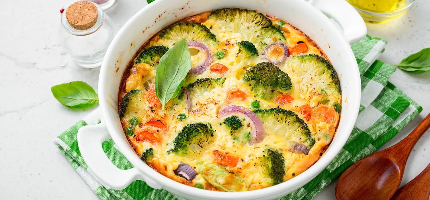 Gemüseauflauf mit Brokkoli und Paprika mit Käse überbacken in einer runden Auflaufform.