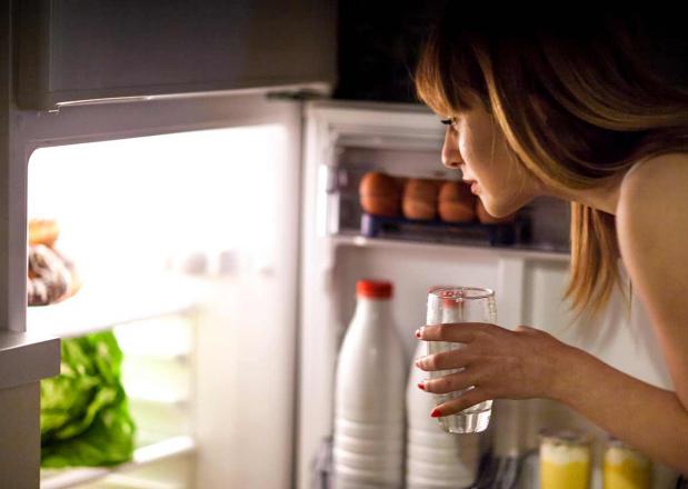 Frau nachts vor geöffnetemKühlschrank