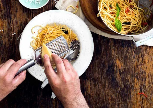 Parmesan wird auf Pasta-Gericht gerieben