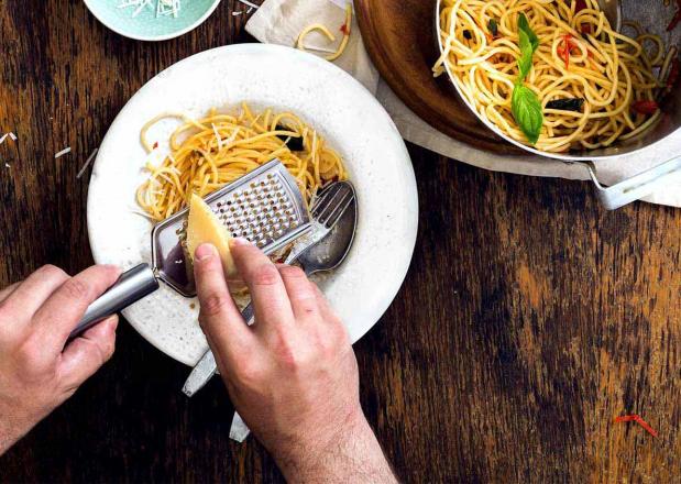 Parmesan wird auf Pasta-Gericht gerieben