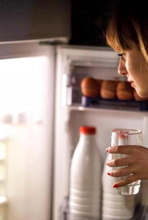 Frau nachts vor geöffnetemKühlschrank