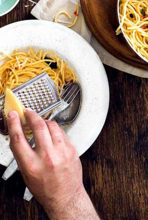 Parmesan wird auf Pasta-Gericht gerieben