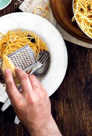 Parmesan wird auf Pasta-Gericht gerieben