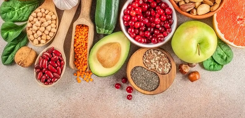 Avocado, Apfel, Cranberries, Zucchini, Spinat, Bohnen, Linsen, Kichererbsen, Nüsse und Samen auf Tischfläche