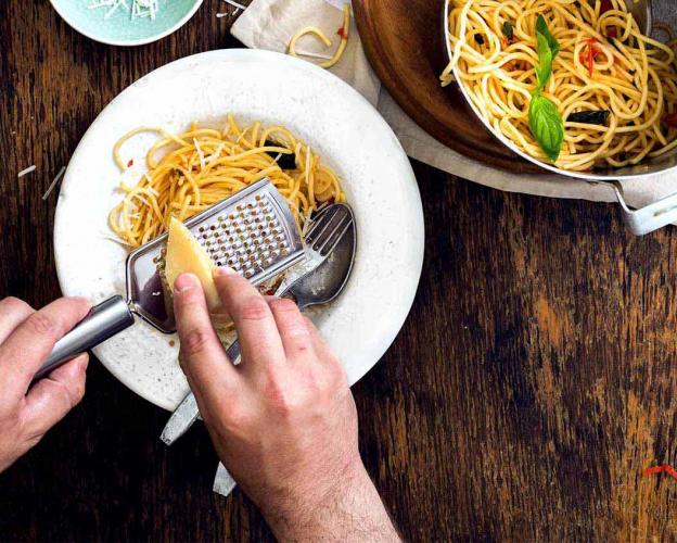 Parmesan wird auf Pasta-Gericht gerieben