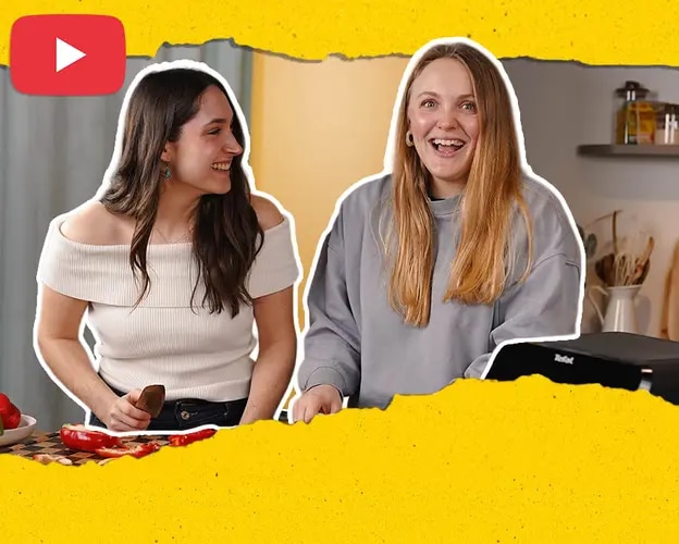 Saskia und Sofie an Küchenarbeitsplatte mit Paprika, Küchenutensilien und YouTube-Logo im Bild