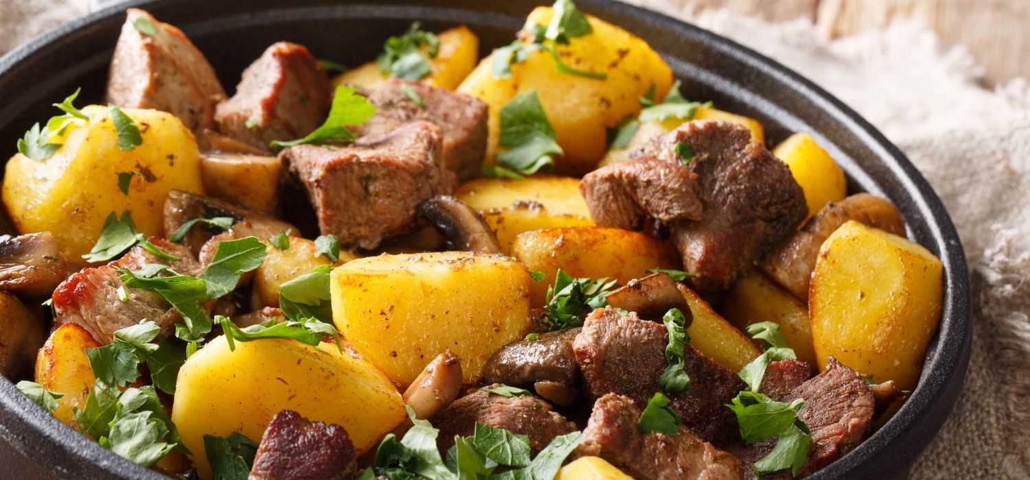 schweinefleisch-mit-kartoffeln-pilzen-kraeutern-in-pfanne