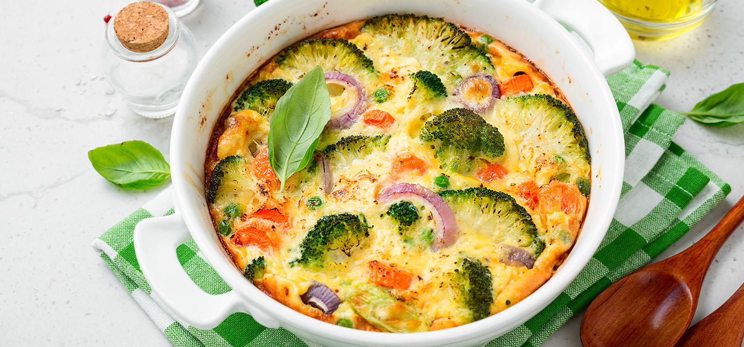 Gemüseauflauf mit Brokkoli und Paprika mit Käse überbacken in einer runden Auflaufform.