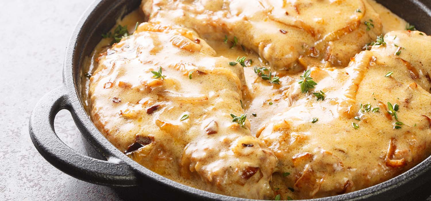 Gebratenes Schnitzel mit Zwiebeln in cremiger Sauce.